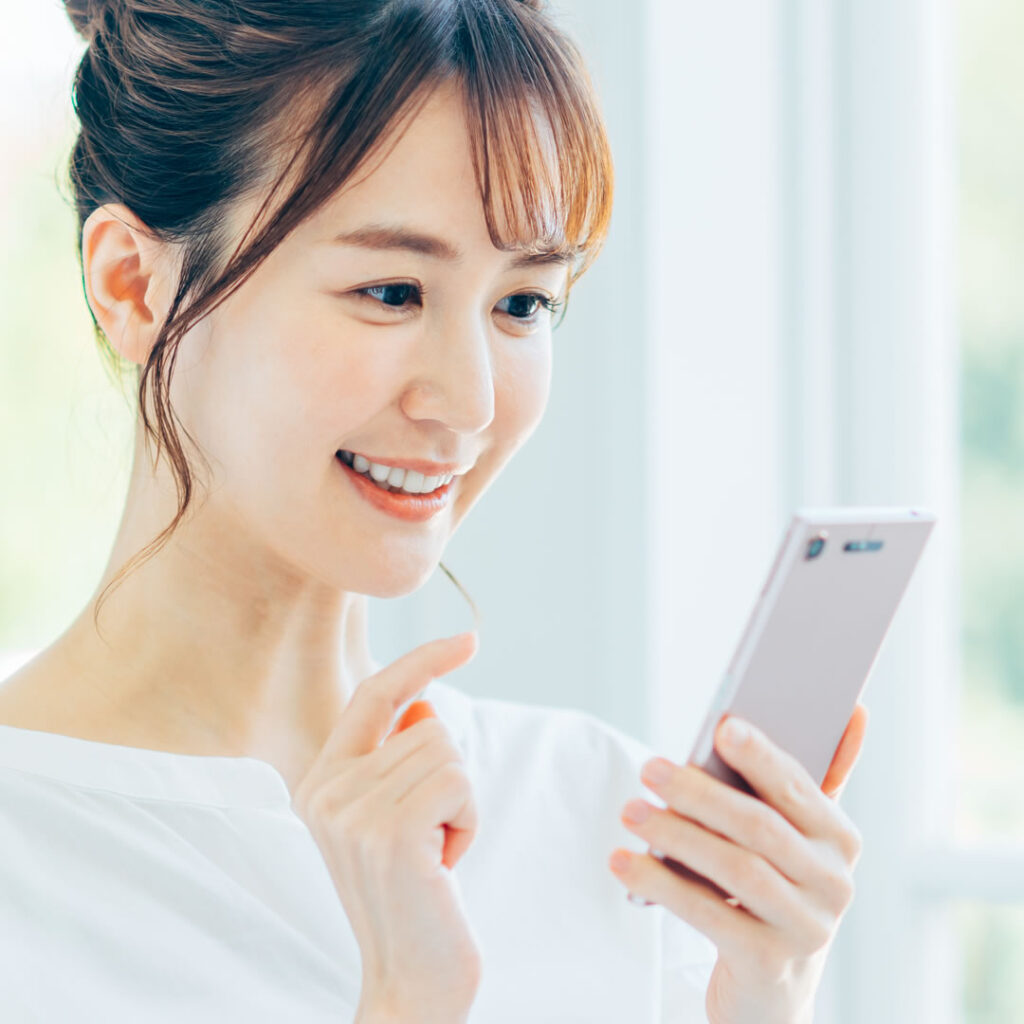 スマフォを見て美容外科の口コミを見ている女性